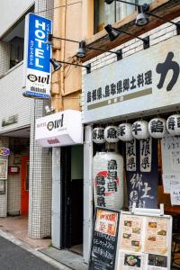 una tienda con letreros al lado de un edificio en Hotel Owl Tokyo Shinbashi, en Tokio