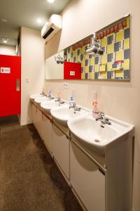 a bathroom with four sinks and a red door at Hotel Owl Tokyo Shinbashi in Tokyo