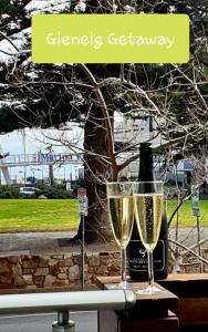 a bottle of champagne and two glasses on a table at Glenelg Getaway 3 bedroom apartment when correct number of guests are booked in Glenelg