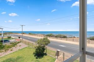 a view from a window of a road and the ocean at Pearl by the Sea in Aldinga Beach