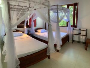 two beds with white drapes in a bedroom at Lotus Villa Kandy in Peradeniya