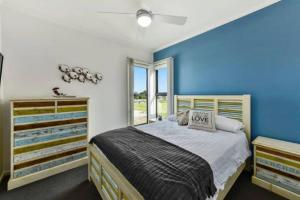 a bedroom with a bed and a blue wall at Plovers Rest at Cape Douglas in Cape Douglas