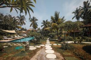 a resort with a swimming pool and palm trees at Segar Village in Gili Islands