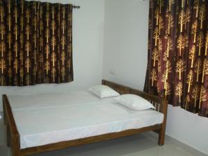 a bed with two pillows in a room with curtains at Jacaranda Holiday Home in Cochin