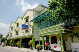 un bâtiment vert et blanc dans une rue dans l'établissement OYO Life 2508 Alba Suites Homestay Syariah, à Tulungagung