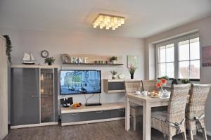 a living room with a television and a dining room table at Bellevue 12 in Laboe