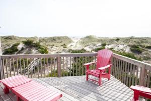 a red chair and a bench on a deck with the beach at 40310 B Due East Lane Duplex Townhouse in Avon