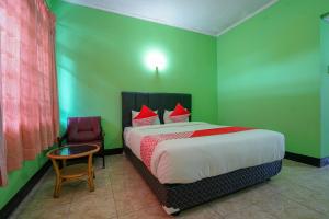 a bedroom with a bed and a table and a chair at Super OYO 1389 Hotel Carissima in Palembang