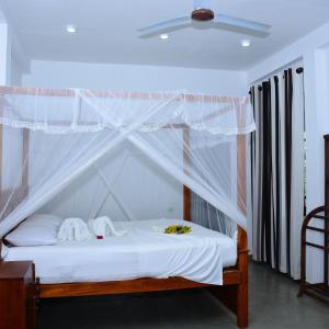 a bedroom with a canopy bed with white sheets at Little Sunshine Guest House & Restaurant in Tangalle