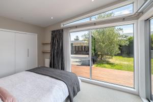 a bedroom with a bed and a large window at Wind Down on Esther in Martinborough 
