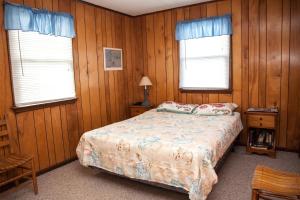 a bedroom with wooden walls and a bed and two windows at Shoresurf House 54227 in Frisco
