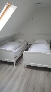 two white beds in a room with wooden floors at Vakantiehuisje Lora in Middelkerke