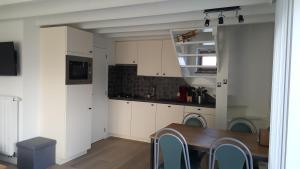a kitchen with white cabinets and a wooden table at Vakantiehuisje Lora in Middelkerke