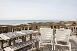 a wooden table and chairs on a deck with the ocean at THE SUNNY SPOT cottage in Frisco