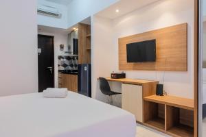 ein Schlafzimmer mit einem Bett, einem Schreibtisch und einem Fernseher in der Unterkunft Minimalist Studio Apartment at Casa De Parco By Travelio in Samporo