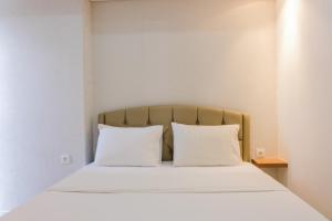 ein Bett mit zwei weißen Kissen in einem Zimmer in der Unterkunft Minimalist Studio Apartment at Casa De Parco By Travelio in Samporo + 11 Fotos