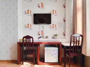 芹苴的住宿－湄公河櫻桃酒店，一张桌子、两把椅子和墙上的电视