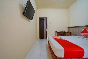 a bedroom with a bed and a tv on the wall at OYO Life 2502 Syariah Triantama Kost in Palembang
