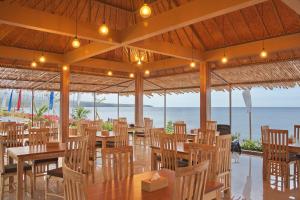 un restaurante en la playa con mesas y sillas en Seamount Hotel Amed en Amed