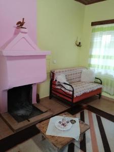 sala de estar con chimenea rosa y mesa en Ktimata Evdoxia, en Platanoússa