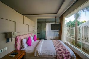 a bedroom with a bed with pink pillows and a balcony at Ocean View Residence in Jepara