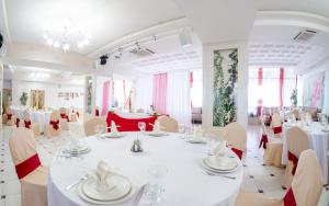 comedor grande con mesas y sillas blancas en AMAKS Omsk Hotel, en Omsk