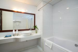 La salle de bains blanche est pourvue d'une baignoire, d'un lavabo et d'un miroir. dans l'établissement Serene Boutique Hotel & Spa, à Hanoï
