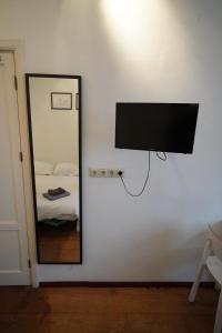 a mirror on a wall with a television and a bed at Kerkstraat Bed and Breakfast Apartment with private Garden in Amsterdam