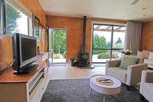 sala de estar con TV de pantalla plana y sofá en Amuri Estate Luxury Lodge en Hanmer Springs