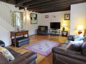 uma sala de estar com sofás de couro e uma televisão em Harleyburn Cottages - Stables and Saddlery em Melrose