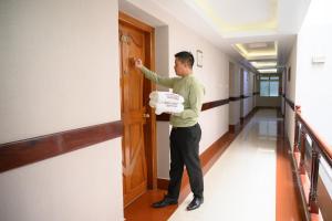 a man is opening a door in a hallway at The Classic Hotel in Imphal