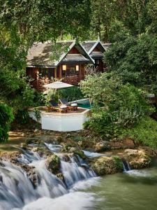 琅勃拉邦的住宿－紅木瑯勃拉邦酒店，河边的房屋,有瀑布