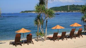 a group of chairs and umbrellas on a beach at Sunset House Gili Meno in Gili Meno