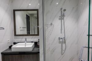 ein weißes Badezimmer mit Waschbecken und Dusche in der Unterkunft Fully Furnished 1BR at Branz BSD City Apartment By Travelio in Samporo + 10 Fotos