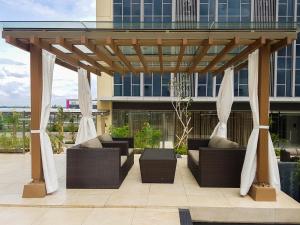 eine Pergola mit Stühlen und Tischen auf einer Terrasse in der Unterkunft Fully Furnished 1BR at Branz BSD City Apartment By Travelio in Samporo