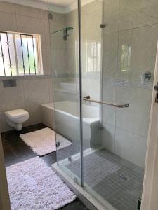 a bathroom with a glass shower and a toilet at White House lodge in Scotburgh in Scottburgh