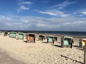 een rij strandstoelen op een zandstrand bij Ferienwohnung Leuchtturmblick in Wangerooge