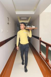 a man walking down a hallway carrying a shelf on his head at The Classic Hotel in Imphal