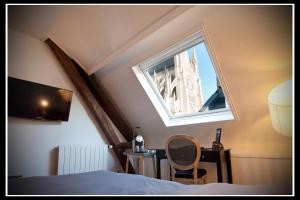 a bedroom with a bed and a large window at Hotel Le Prieuré et La Résidence in Amiens