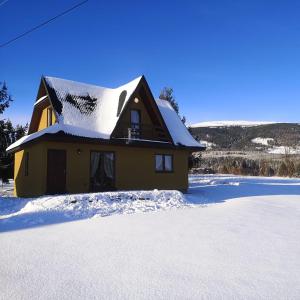 a house with a snow covered roof in the snow at Babiogórski Raj in Lipnica Wielka