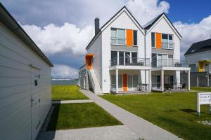 a white house with orange doors and a yard at Marina Lodge in Olpenitz