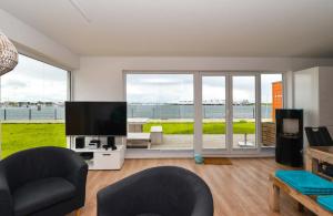 uma sala de estar com uma televisão de ecrã plano e janelas grandes em Marina Lodge em Olpenitz