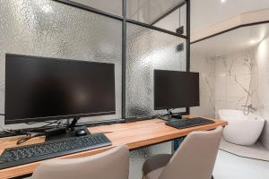 a computer desk with two monitors and a keyboard at Songpa Boutique hotel XYM in Seoul