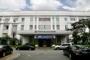 White Palace Thai Binh Hotel في Thái Bình: مبنى ابيض فيه سيارات تقف امامه