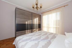 a bedroom with a large bed and a chandelier at Apartman Sulić in Podgora
