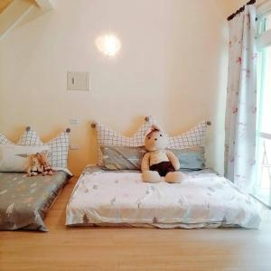 a teddy bear sitting on a bed in a room at Pu Shi Homestay in Yuli