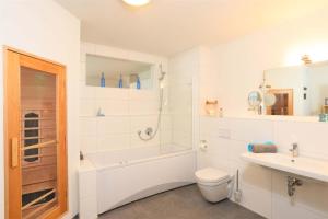 a white bathroom with a tub and a toilet and a sink at Marina Lodge in Olpenitz +23 photos