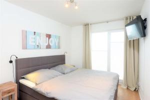 a bedroom with a bed and a tv and a window at Marina Lodge in Olpenitz