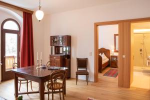 a living room with a table and chairs and a bedroom at Hotel Baur Am See in Dobbiaco