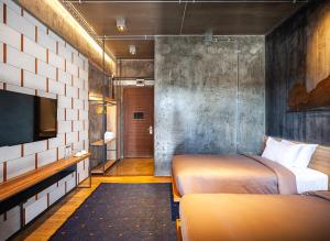 a hotel room with two beds and a tv at Navakitel Design Hotel in Nakhon Si Thammarat